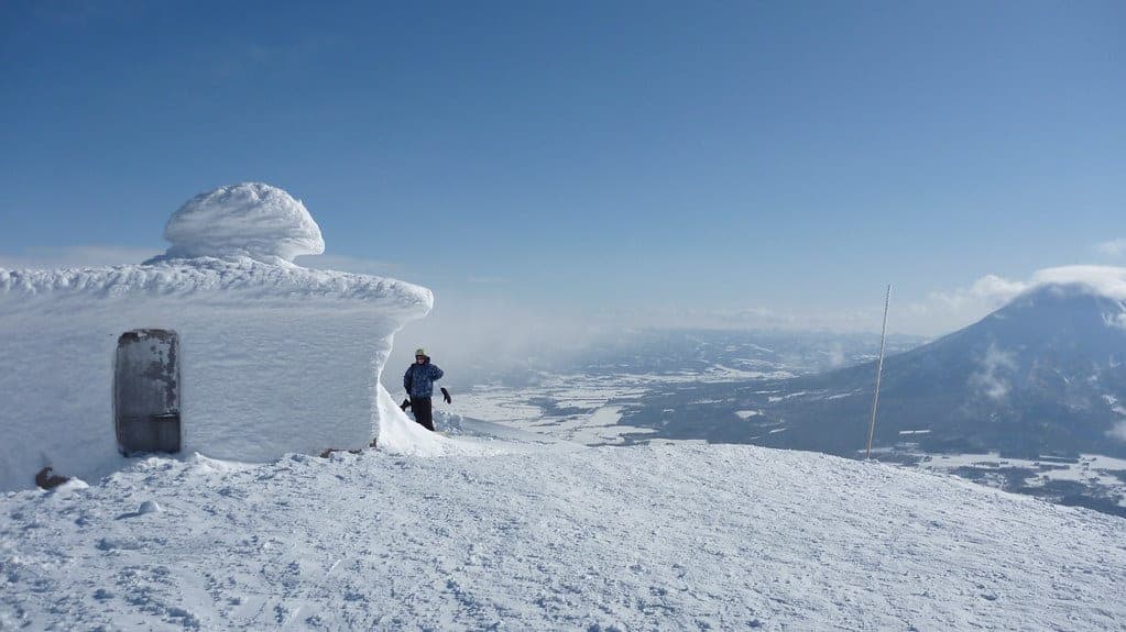 A rime-crusted hut sits on the summit of Niseko Annupuri with the valley below