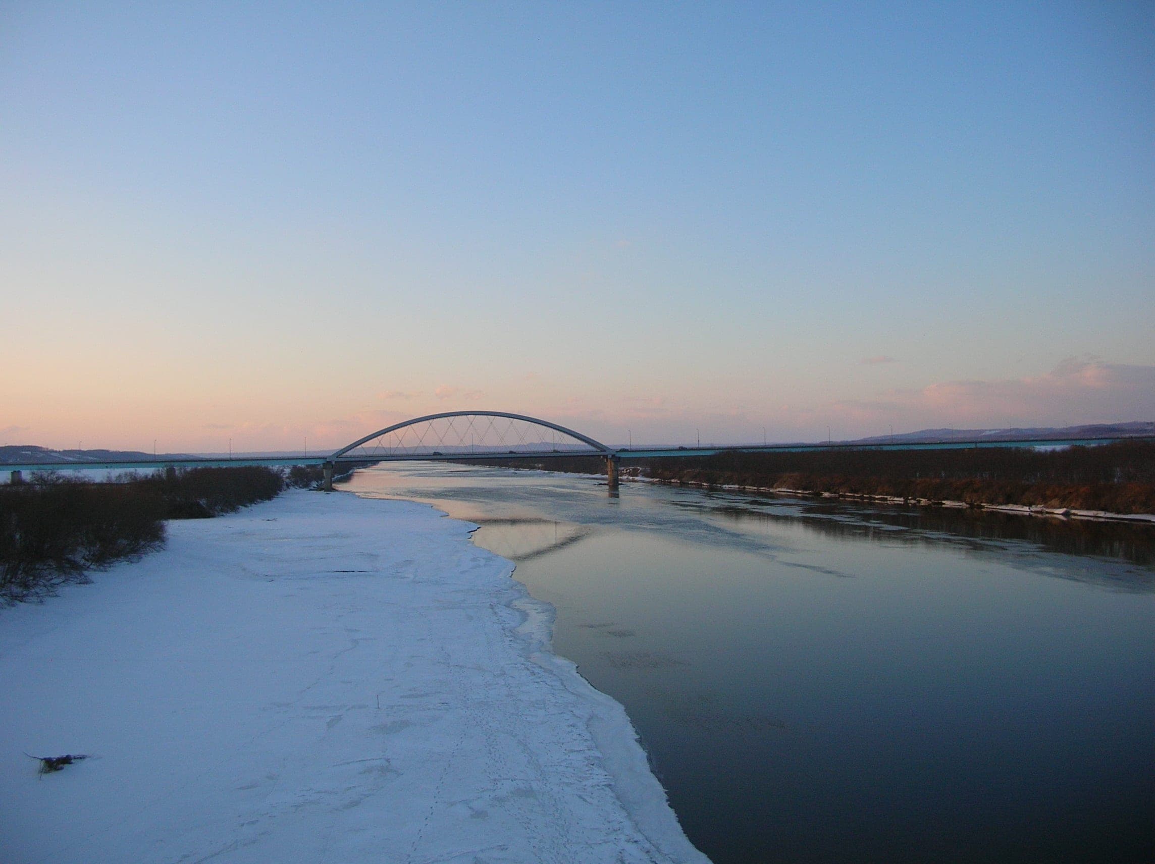 The Toyokoro Bridge arches over the Tokachi River on a winter evening