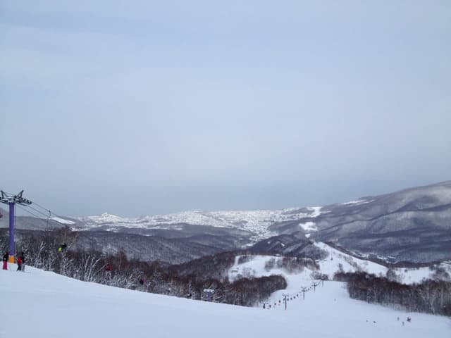 Asarigawa Onsen ski runs drop away below the top of the Purple lift on a clear winter day