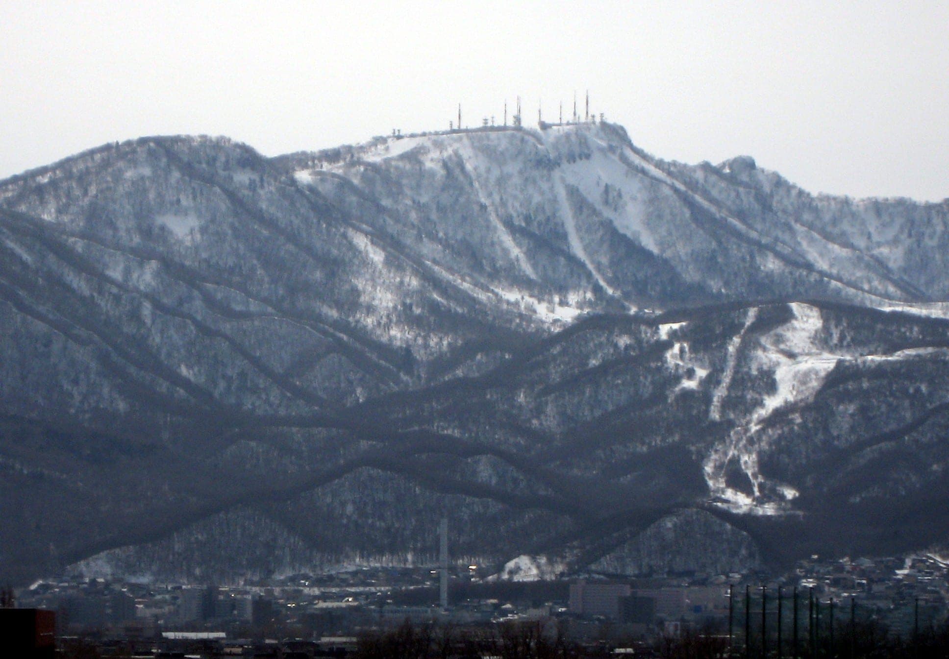 Mount Teine's ski runs streak its snowy, forested slopes, seen from Ishikari