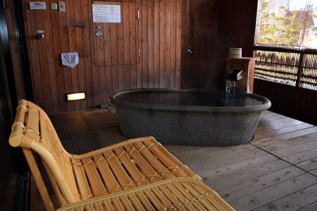 A stone tub of onsen water sits on the timber balcony of a suite at Akan Tsuruga Besso Hinanoza