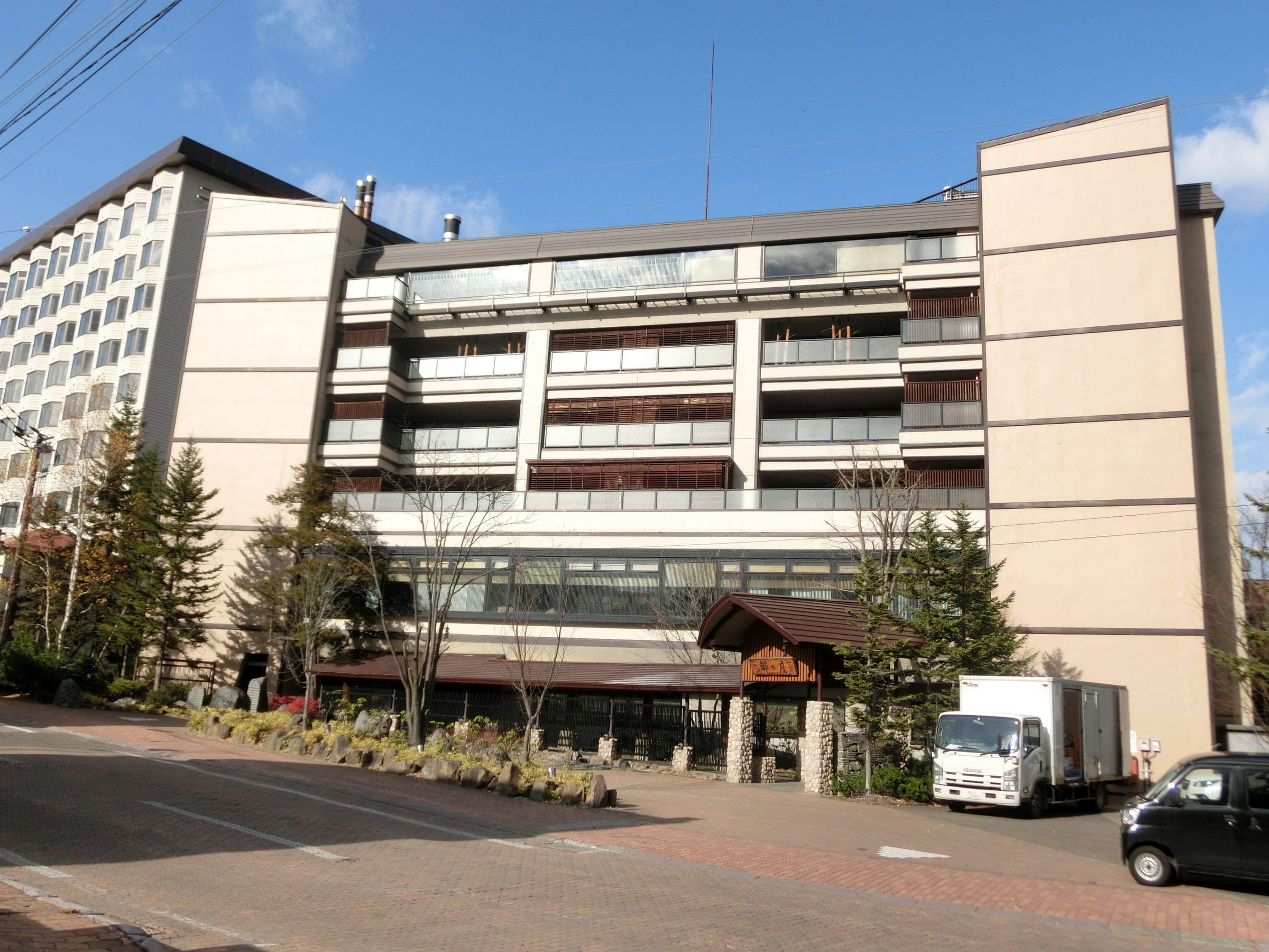 Akan Tsuruga Besso Hinanoza rises above the main street of Akanko Onsen under a clear sky