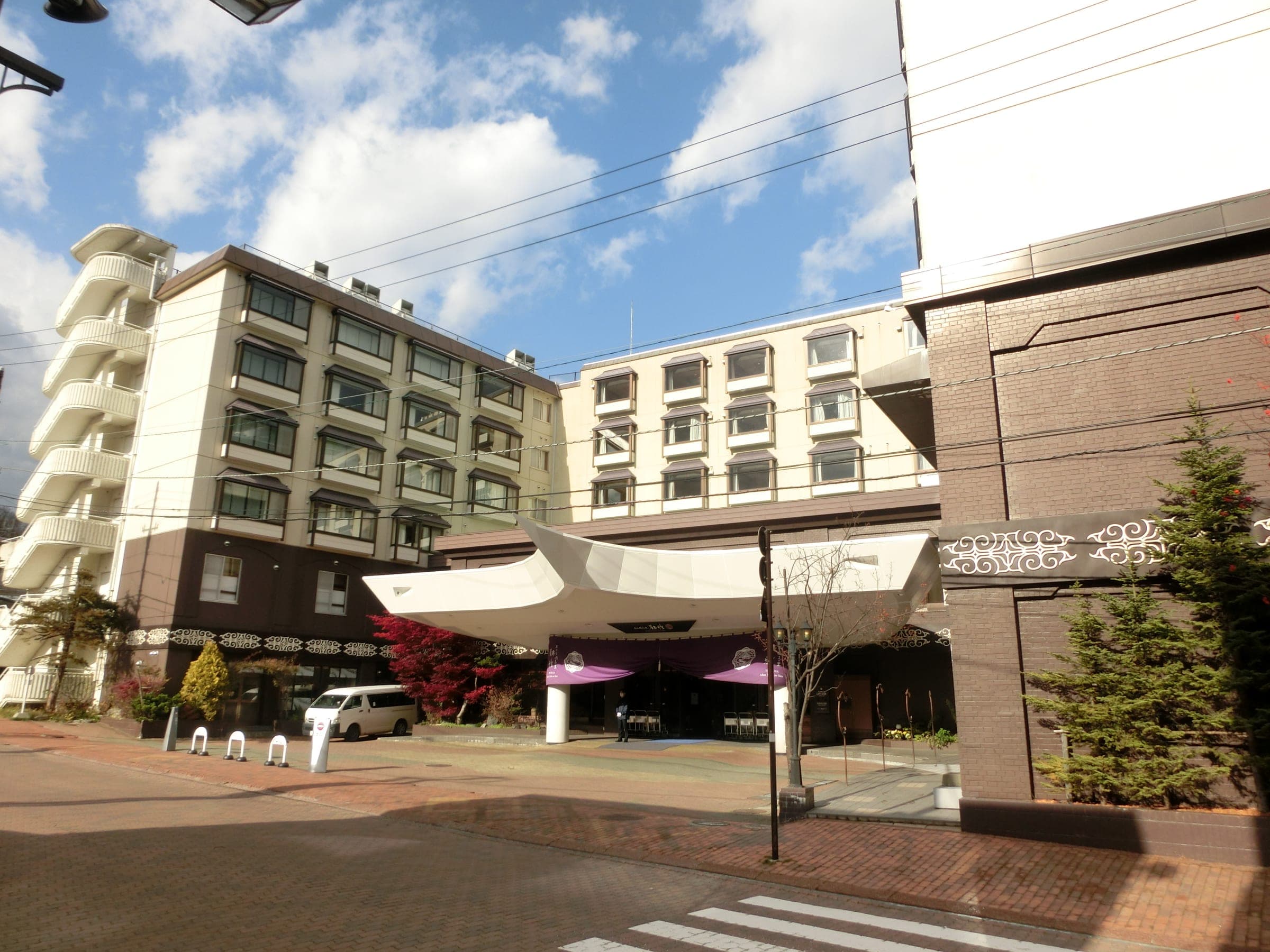 A curved white canopy shelters the entrance of Akan Yuku no Sato Tsuruga in Akanko Onsen