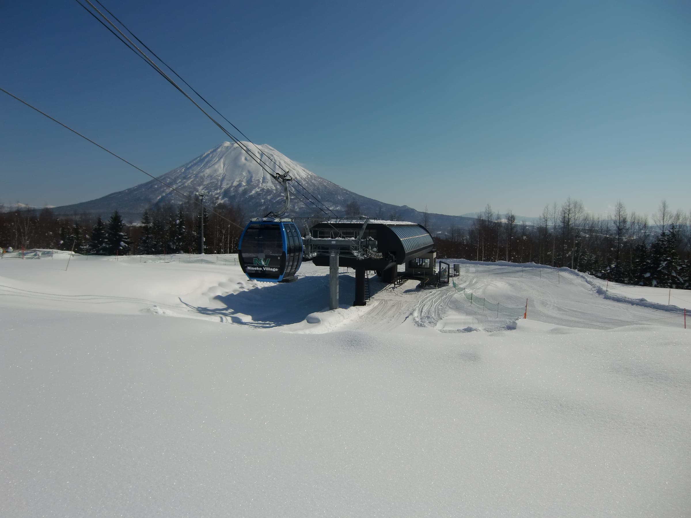 Mt. Yotei rises behind a Village Express cabin on the snowy upper slopes of Niseko Village