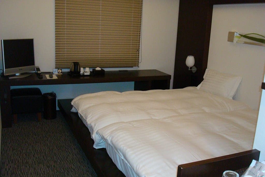 A low double bed and a dark timber desk fill a guest room at Furano Natulux Hotel