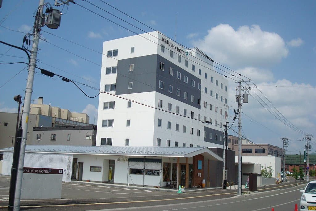 Furano Natulux Hotel rises in white and grey above its low entrance wing near JR Furano Station