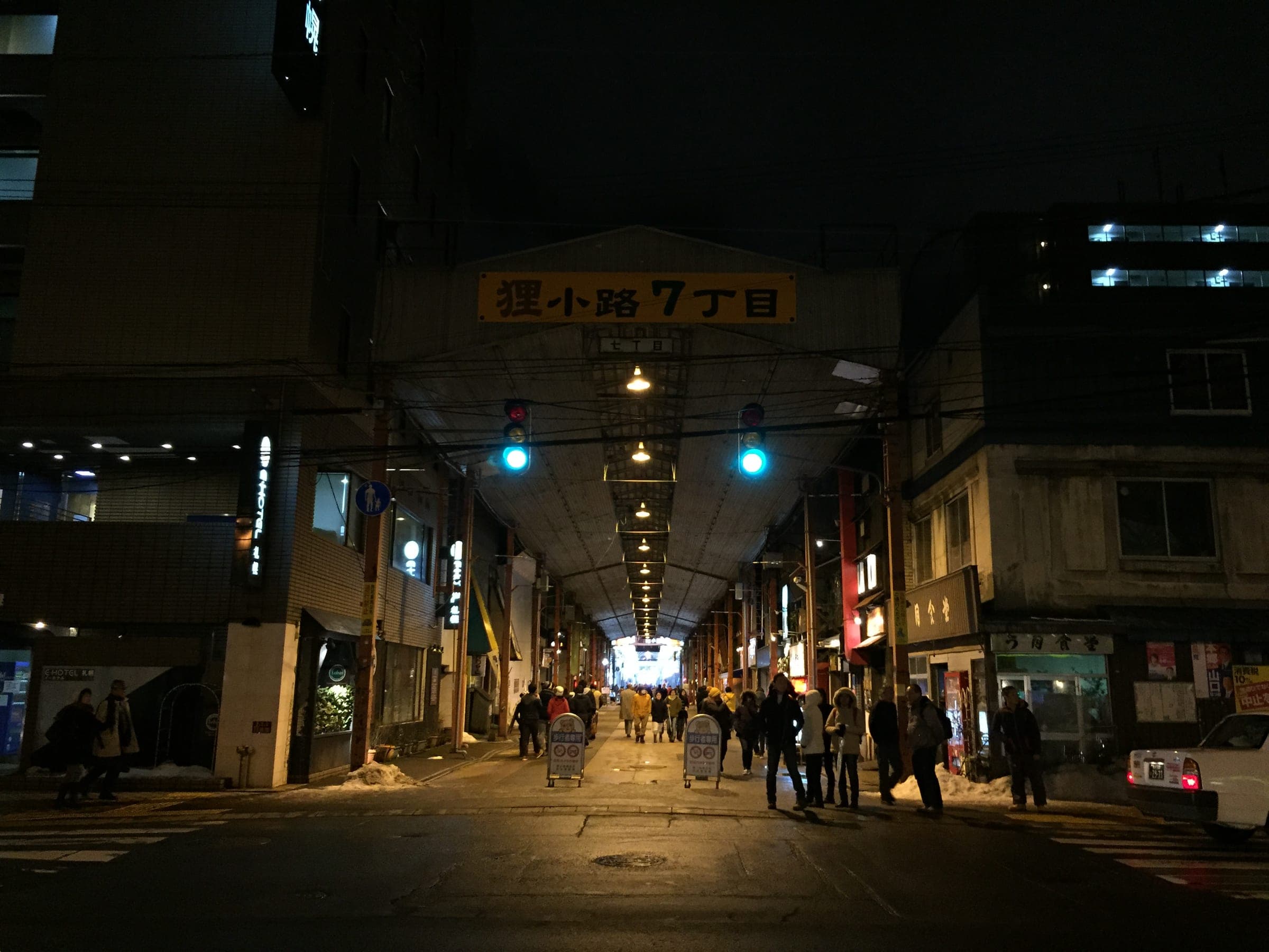 Shoppers walk into the Tanuki Koji 7-chome arcade on a winter night near Grand Hostel LDK Sapporo