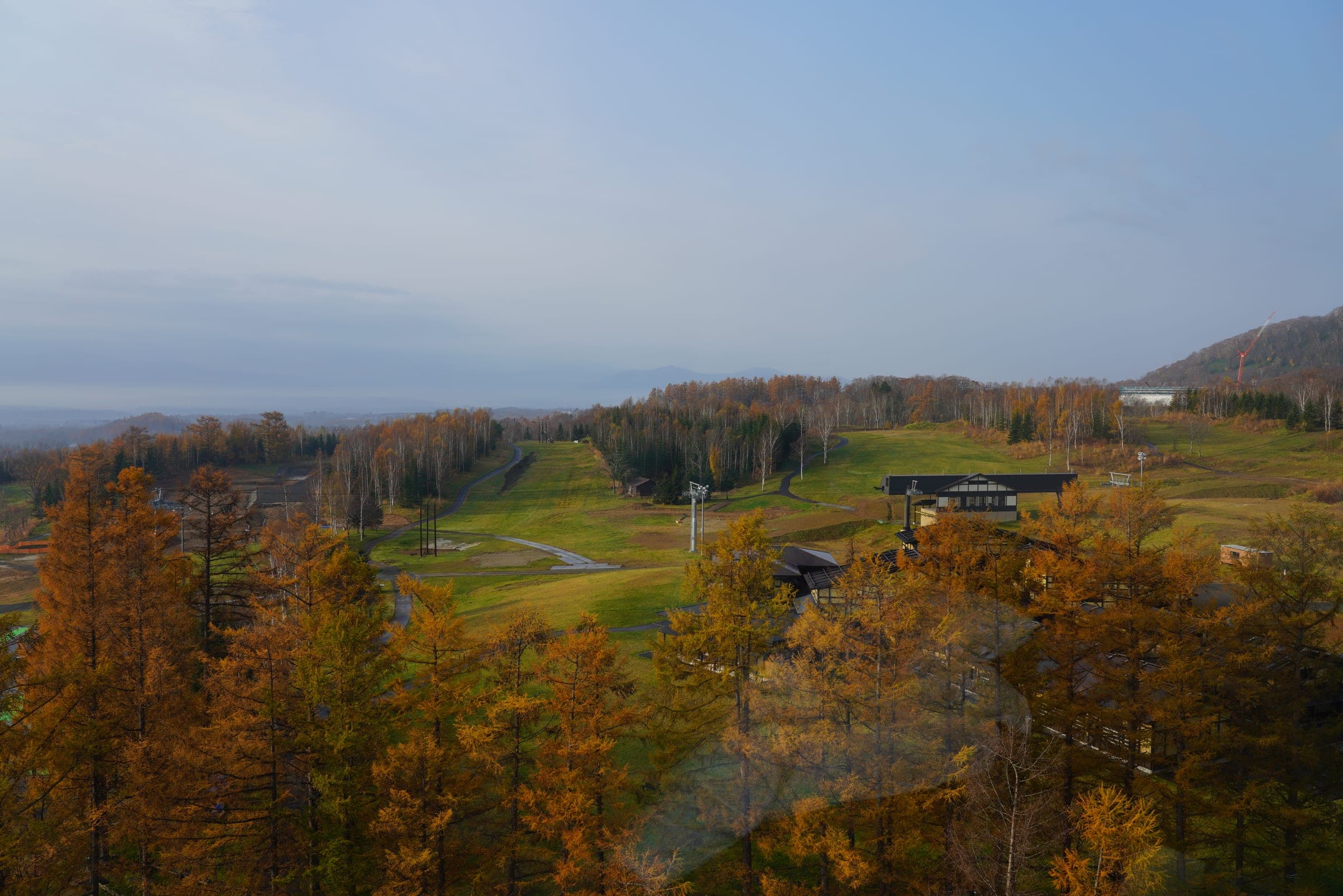 Autumn larch forest and the Niseko Village golf course seen from high in the Hilton Niseko Village