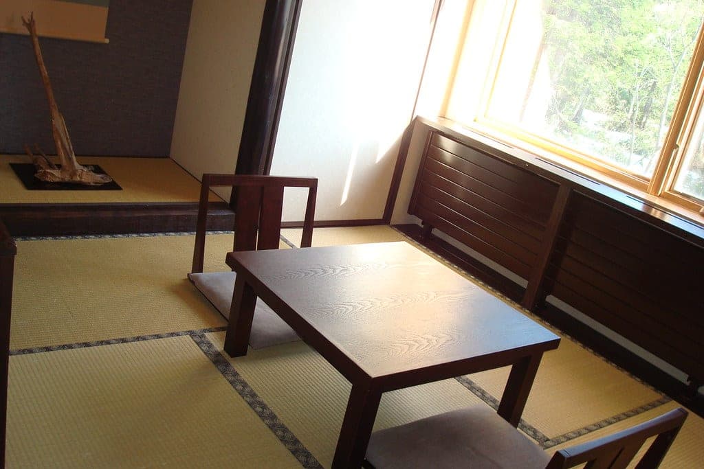 A tatami guest room at La Vista Daisetsuzan with a low table, chairs and a window onto the trees