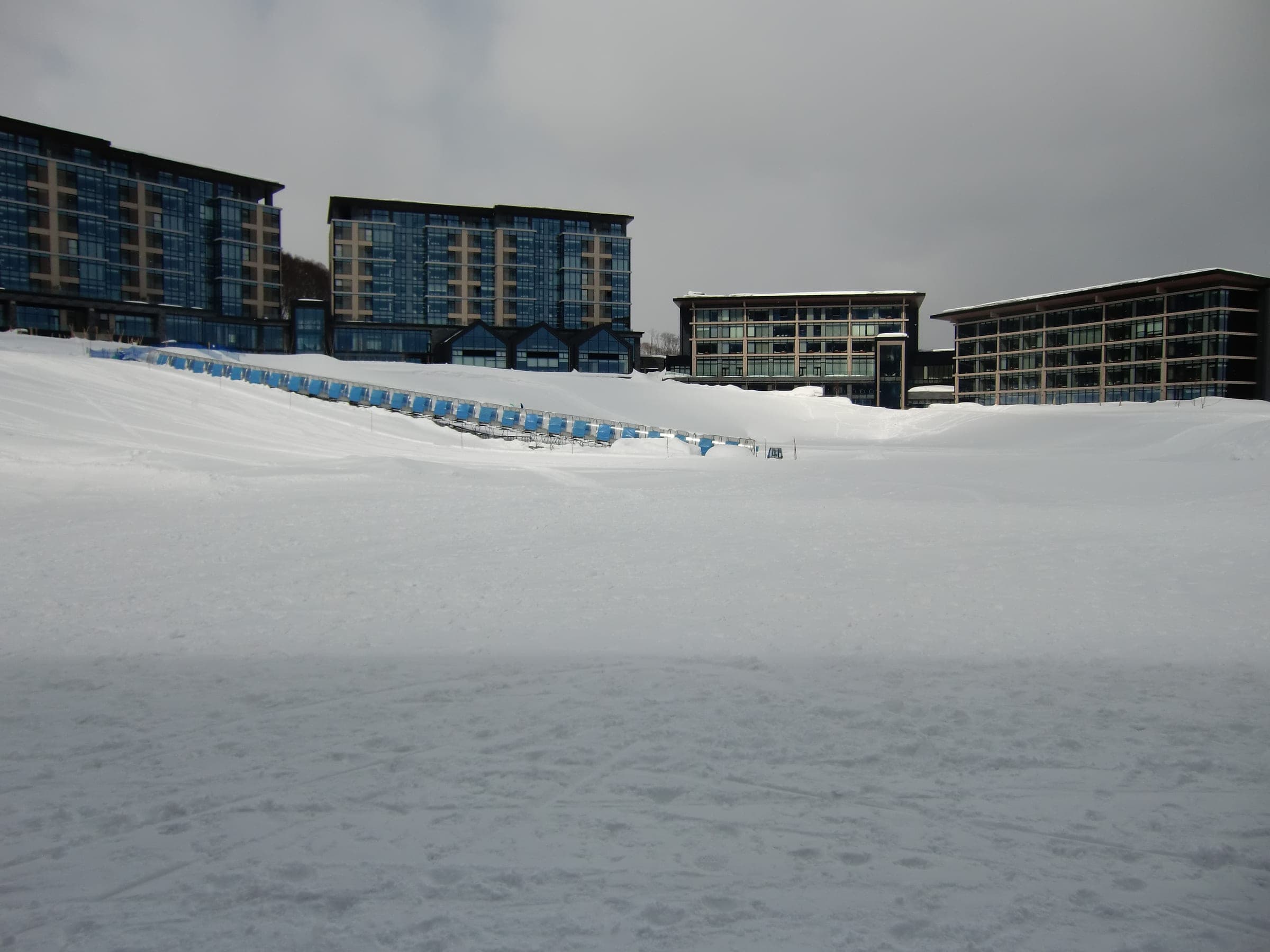 Park Hyatt Niseko Hanazono seen across the snow of the Hanazono tube park on a grey day