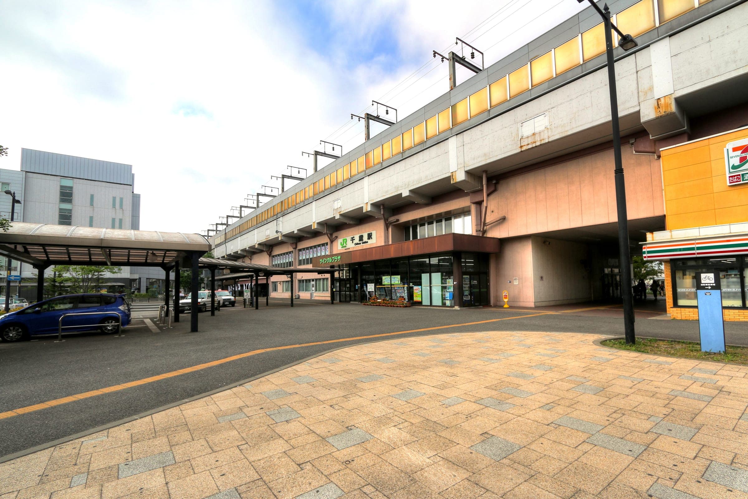 A paved plaza and covered walkway run beside the elevated Chitose Station building
