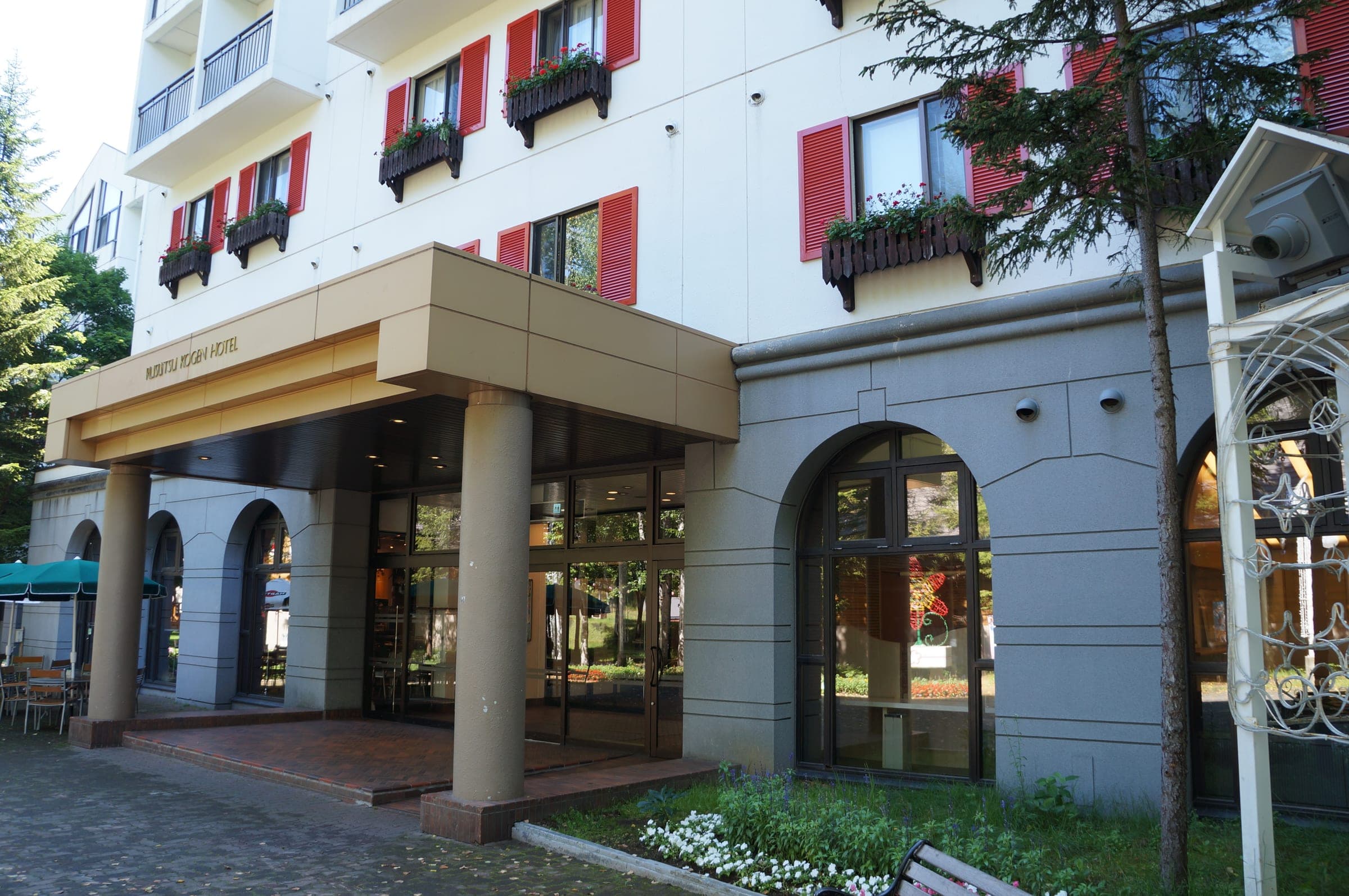 The arched entrance of Rusutsu Resort Hotel under window boxes and red shutters