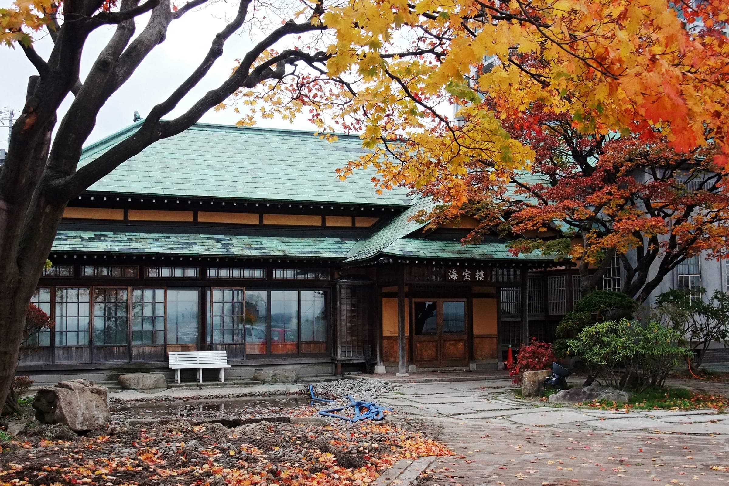 Autumn maples frame the green-roofed Japanese wing of the former Itaya Residence, now Tabist Kaihorow, in Otaru