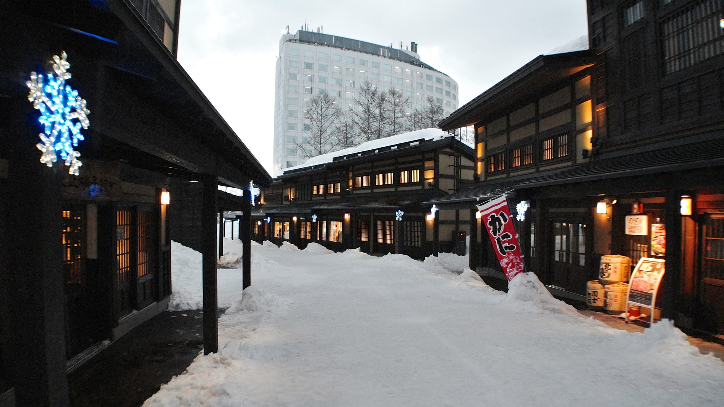 Snow fills the lane between the timber shops of Niseko Village beside the resort hotels