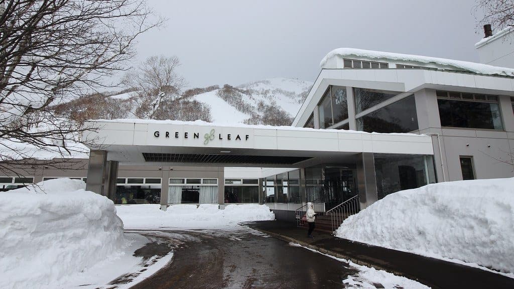Snowbanks line the drive to the white entrance canopy of The Green Leaf at Niseko Village