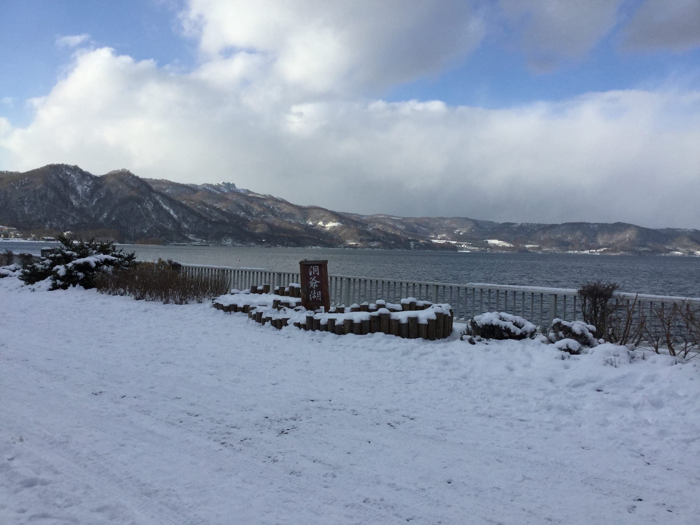 Fresh snow covers the Toyako Onsen lakefront as cloud gathers over the hills across Lake Toya