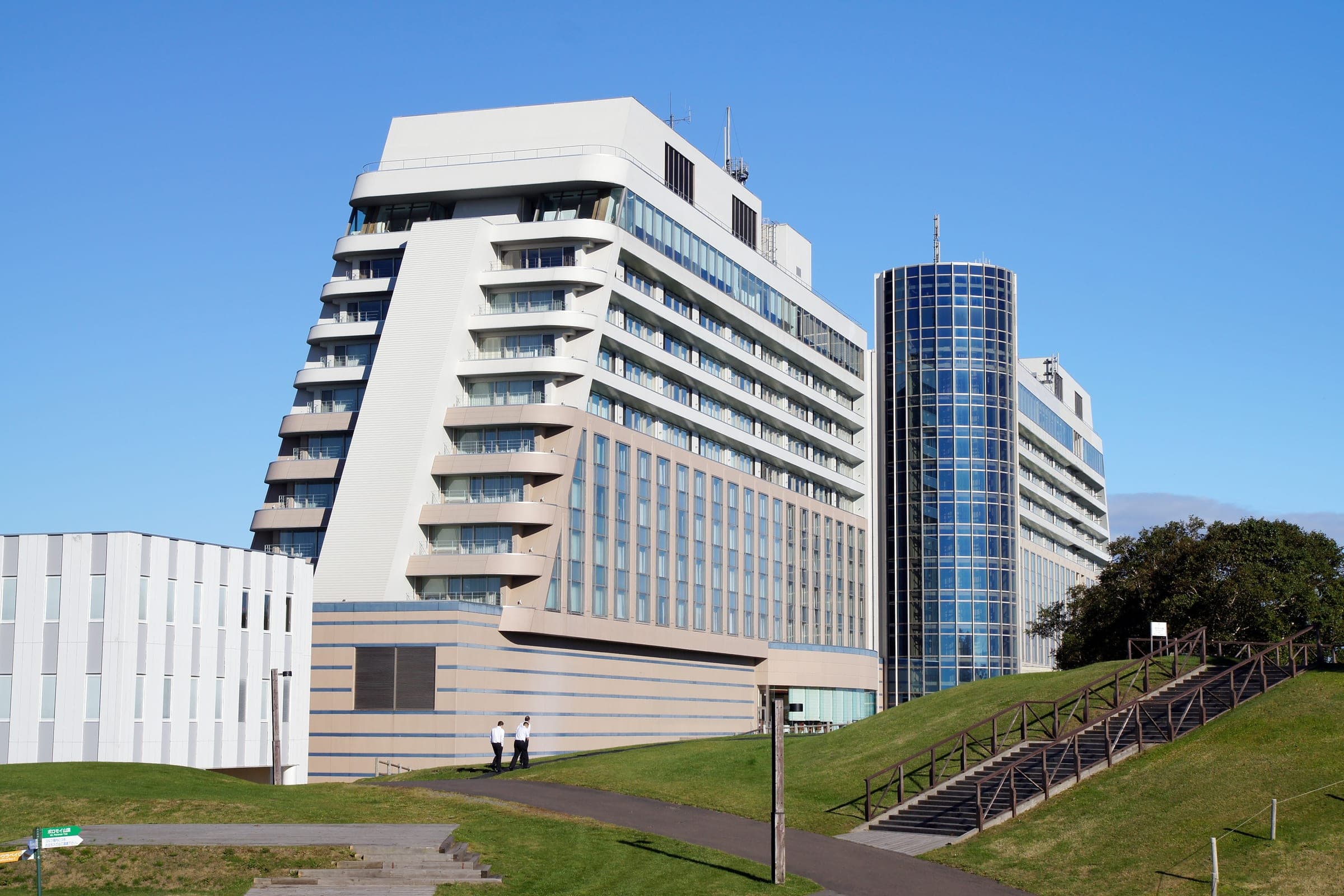 The Windsor Hotel Toya's curved white tower on its ridge under a clear blue sky