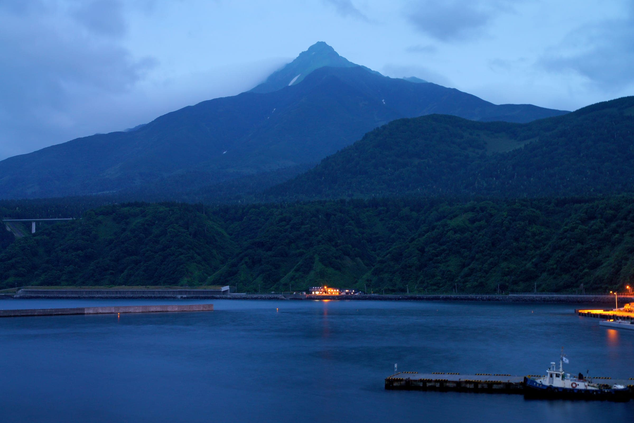 Mount Rishiri rises over Oshidomari Port in the blue light of evening