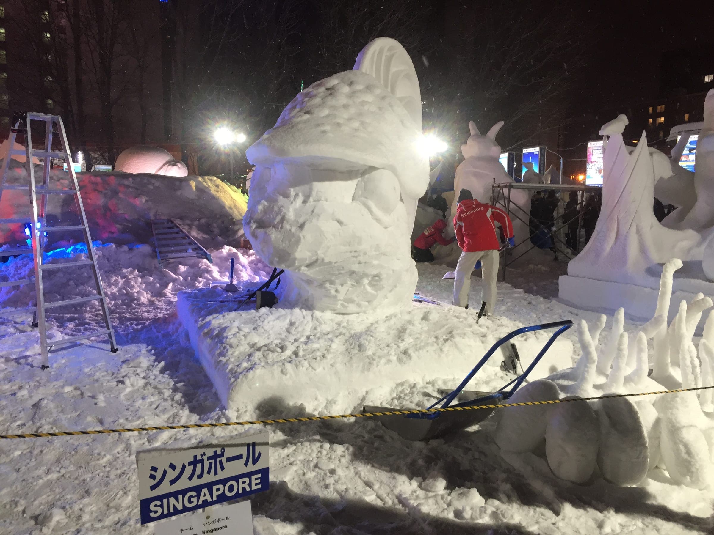 Floodlit snow sculptures line Odori Park at night during the Sapporo Snow Festival