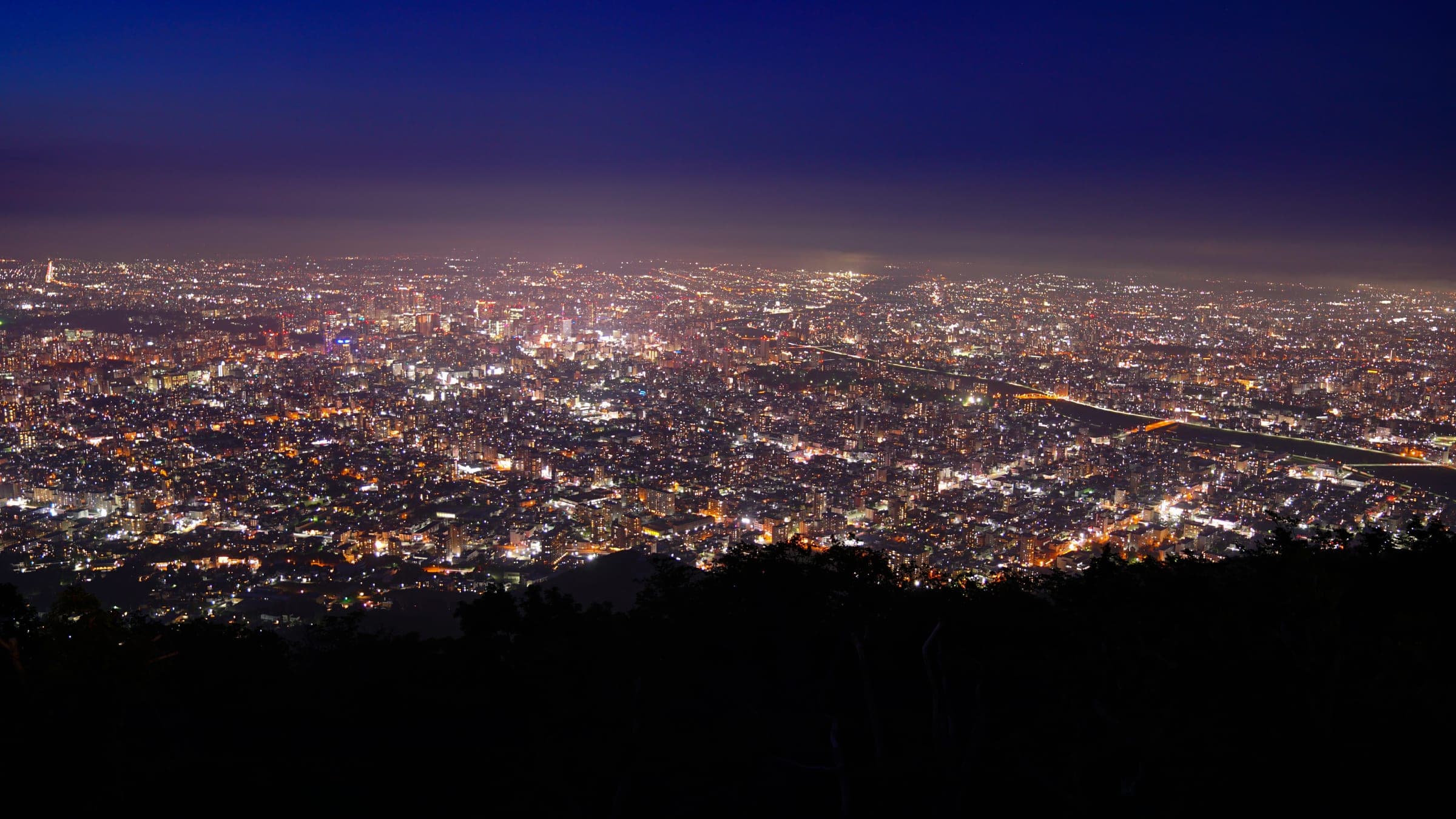 The lit grid of Sapporo spreads out below the summit of Mt. Moiwa at night