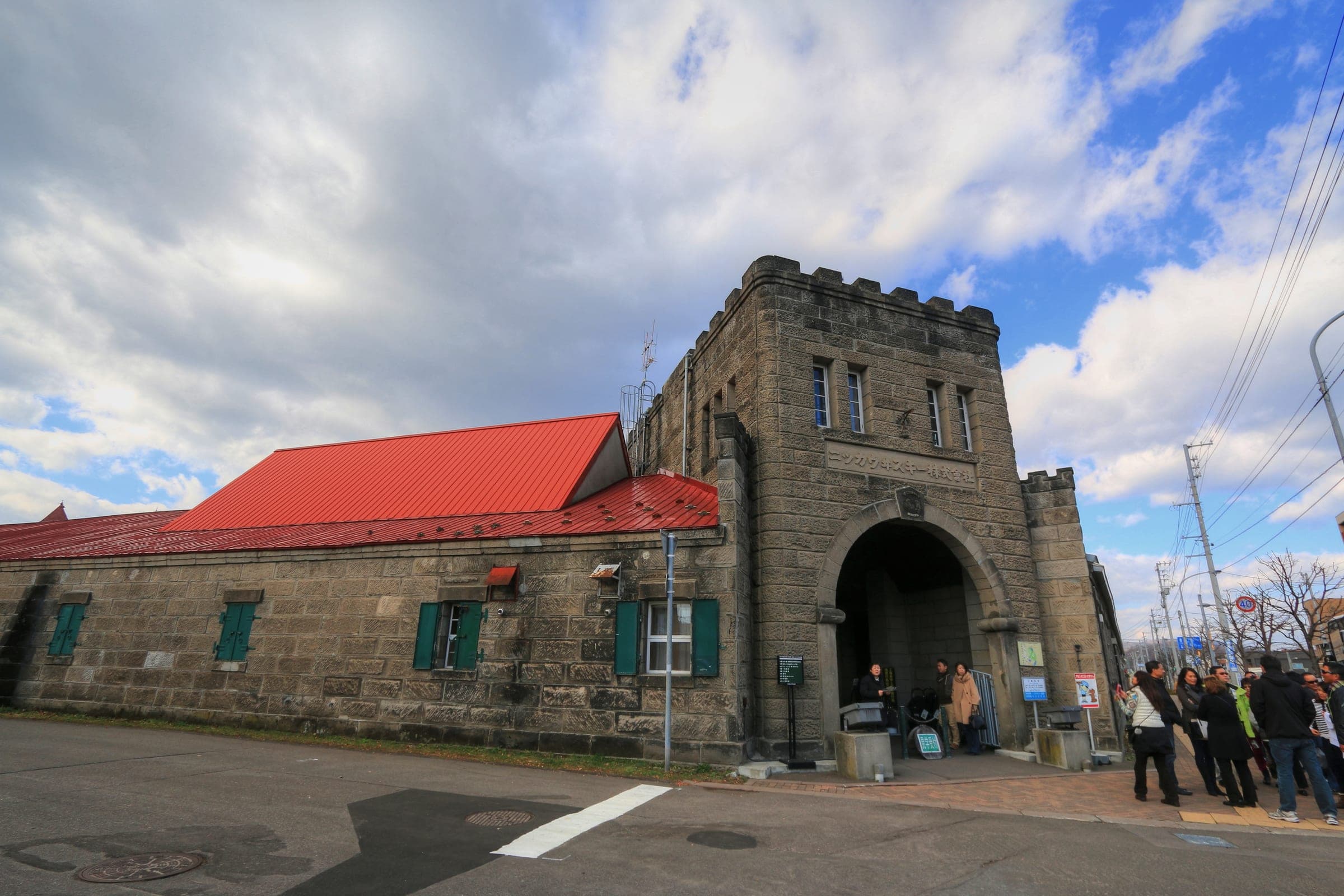The stone gatehouse of the Nikka Yoichi Distillery under a bright summer sky