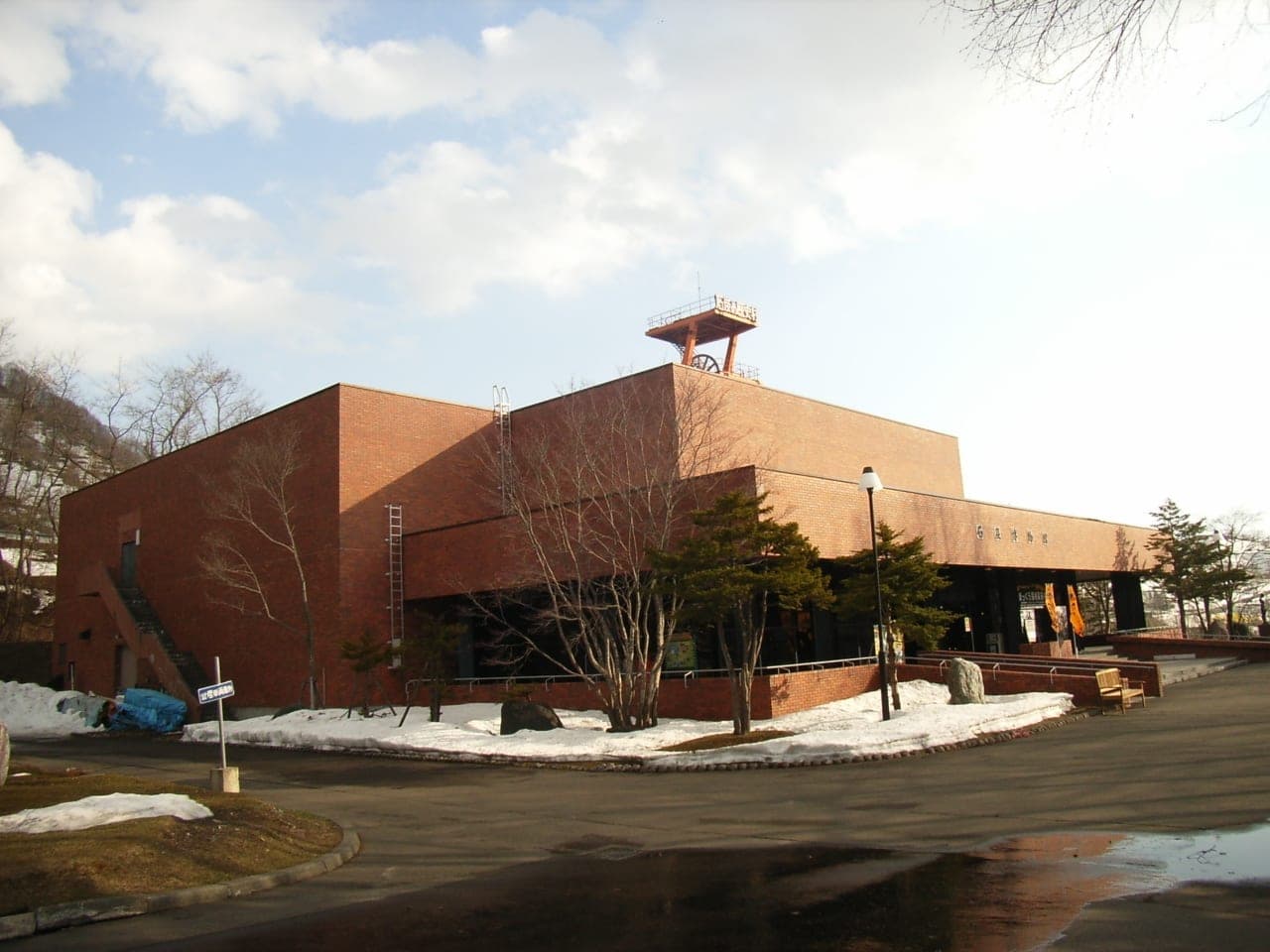 The brick Yubari Coal Mine Museum with late snow on the ground